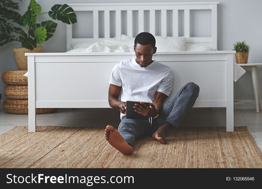 Happy young african american black man with tablet in bedroom in morning. Happy young african american black man with tablet in bedroom in morning