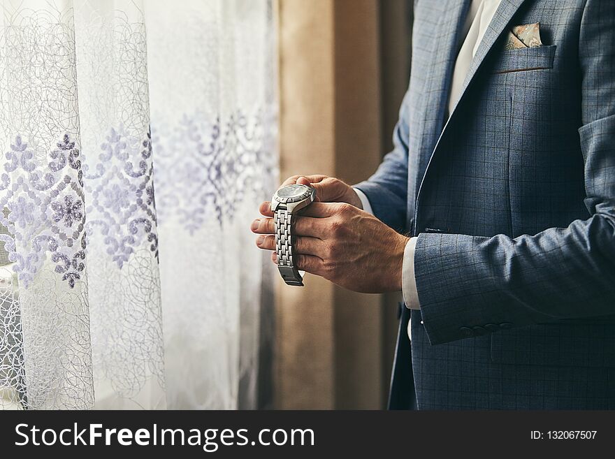 Businessman checking time on his wrist watch, man putting clock