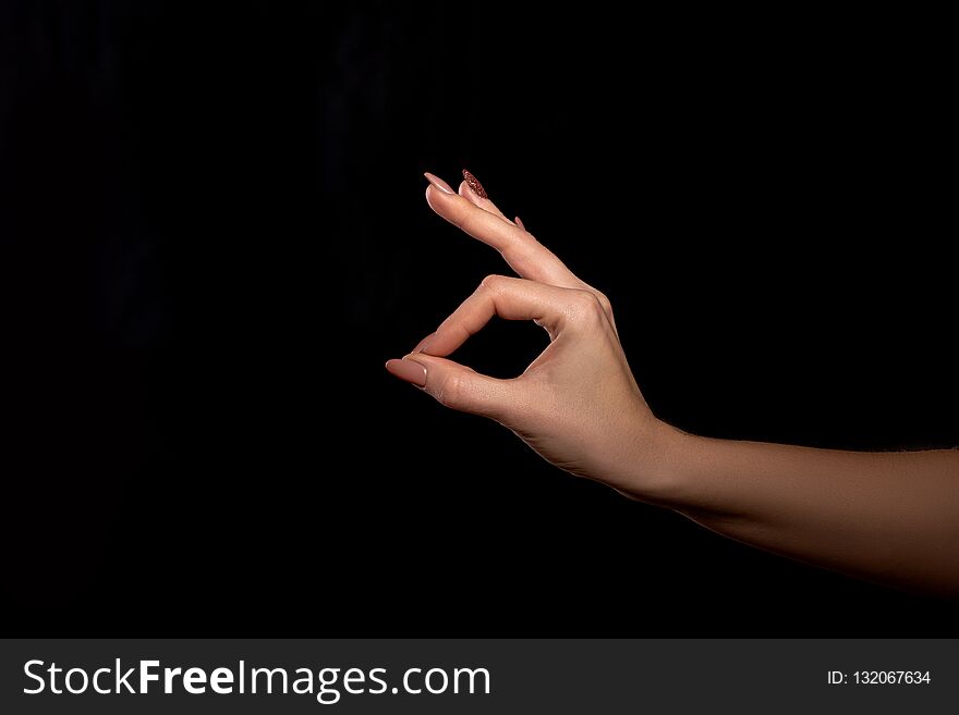 Studio shot of an unidentified woman`s hand showing a gesture of fingers that everything is fine or OK against a black background