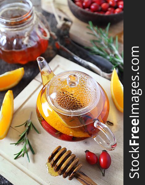 Healthy hot winter beverage. Rose hip tea with oranges in teapot, rosemary and berries. Healthy hot winter beverage. Rose hip tea with oranges in teapot, rosemary and berries