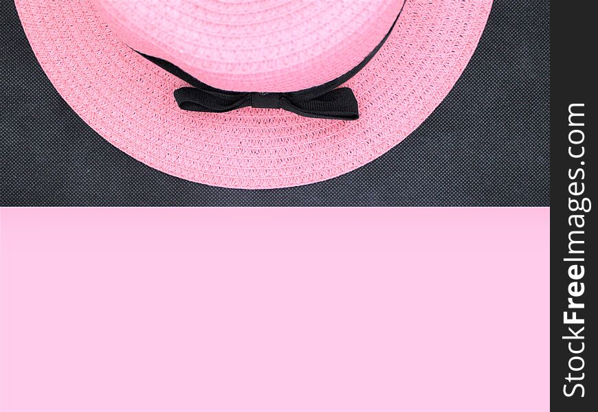 Pink hat with a black bow is lying on a black background. Free space for your signature