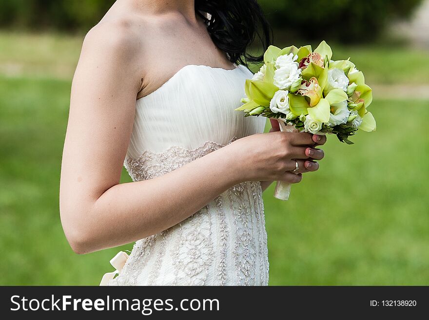 Beautiful wedding bouquet in hands of the bride in park