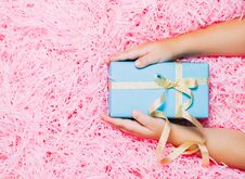 Child Hands Holding Christmas Gift Box On Festive Pink Background. Top View, Flat Lay Stock Photo