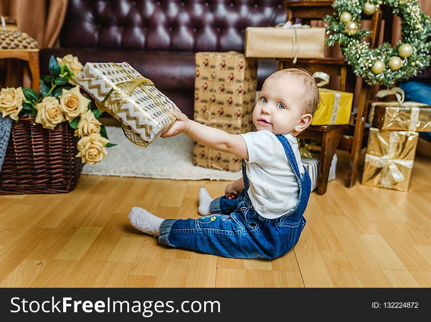 Little girl playing with gold Christmas gifts