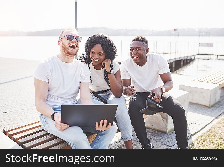 Beautiful multi ethnic friends using a laptop in the Street. Youth lifestyle concept