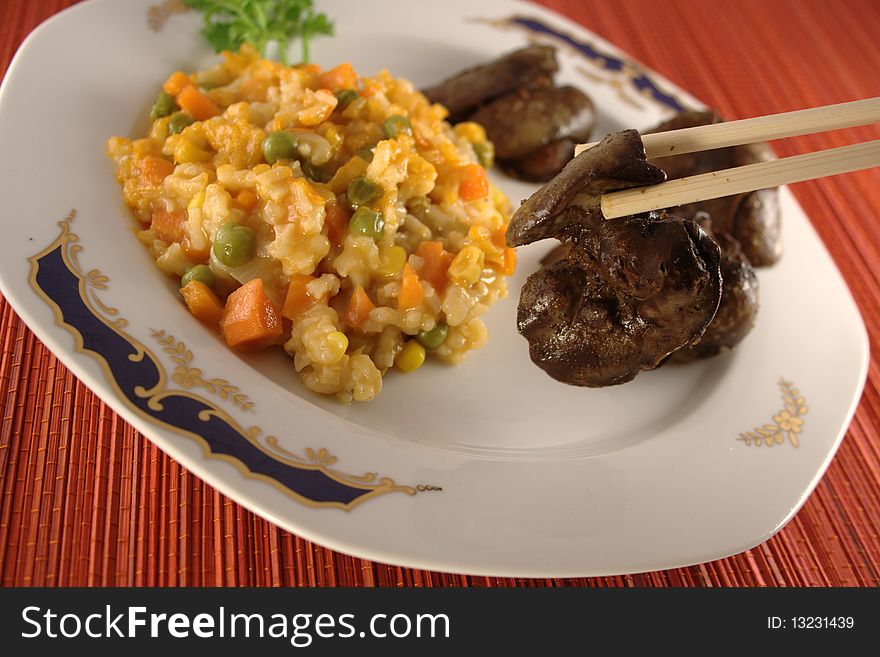 Eating chicken liver and vegetables with chopsticks.