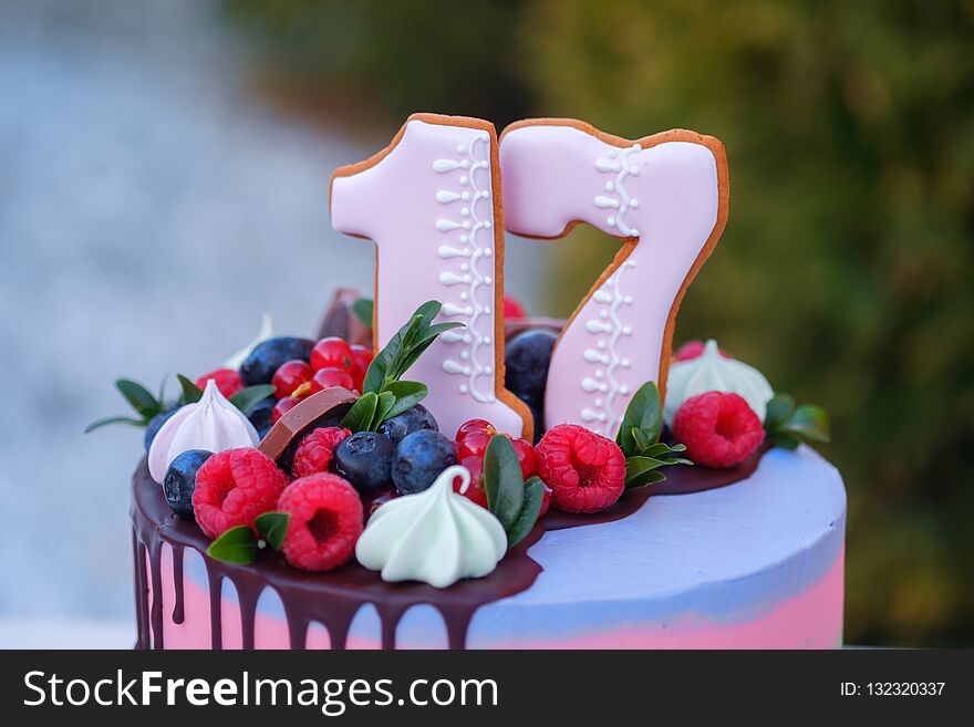 Beautiful birthday cake with the number seventeen, decorated with fresh berries and colorful cream