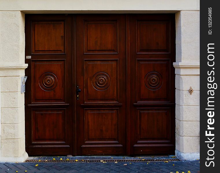 Nicely carved stained red wood gate in stone frame in urban setting. Nicely carved stained red wood gate in stone frame in urban setting