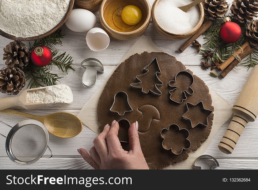 Girl`s hands cook holiday Christmas biscuits with decorative molds on a wooden white background. Top view. Girl`s hands cook holiday Christmas biscuits with decorative molds on a wooden white background. Top view.