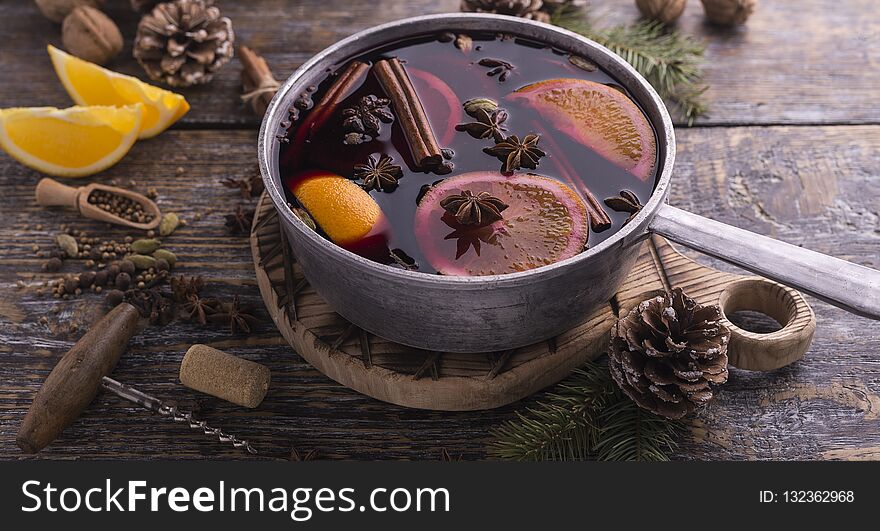 Christmas traditional drink, mulled wine with cinnamon sticks, anise stars, orange fruits on a wooden background. Copy