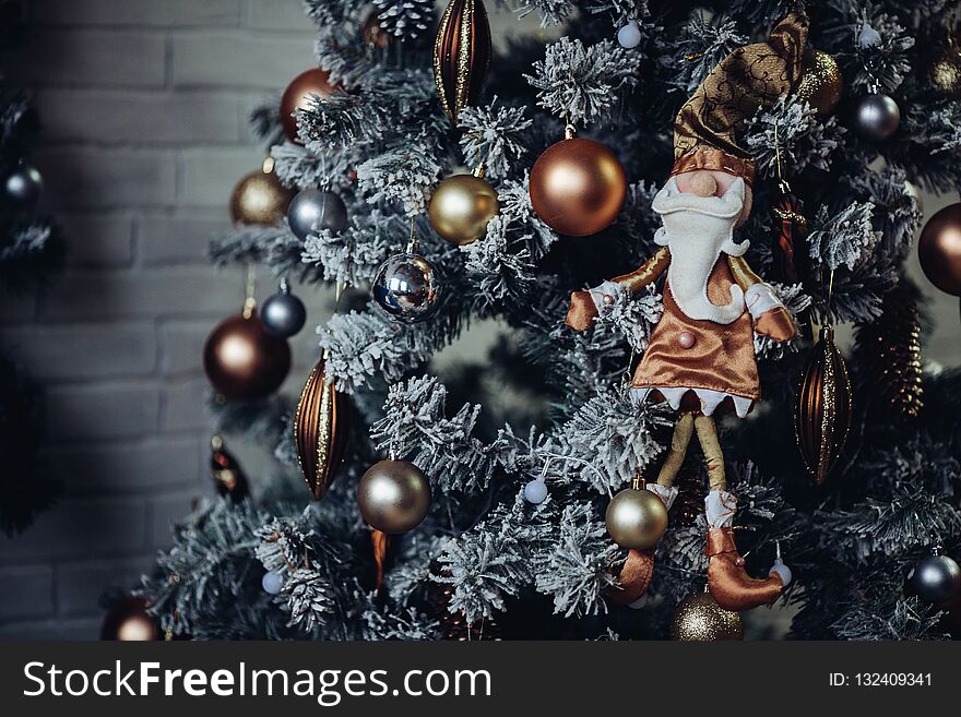 Close up of pine decorated for Christmas gold checkered bows and ribbons. Traditional handmade decoration covered with snowflakes. Concept of Christmas and New Year holidays. Winter season.