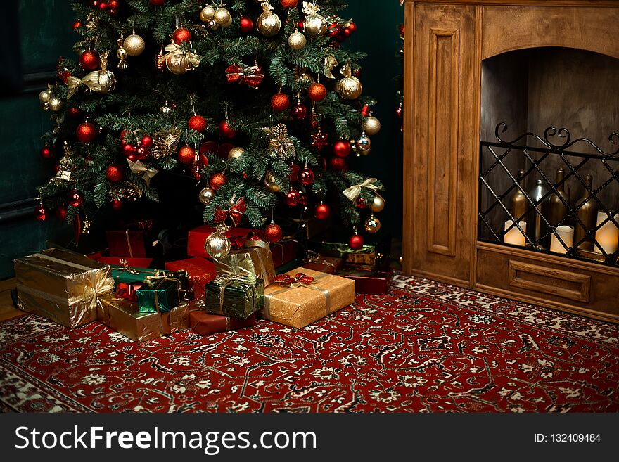 Christmas tree with red checkered bows and ribbons and many gifts and box near. Traditional handmade decoration covered with snowflakes. Concept of Christmas festive mood at home near fire place. Christmas tree with red checkered bows and ribbons and many gifts and box near. Traditional handmade decoration covered with snowflakes. Concept of Christmas festive mood at home near fire place.