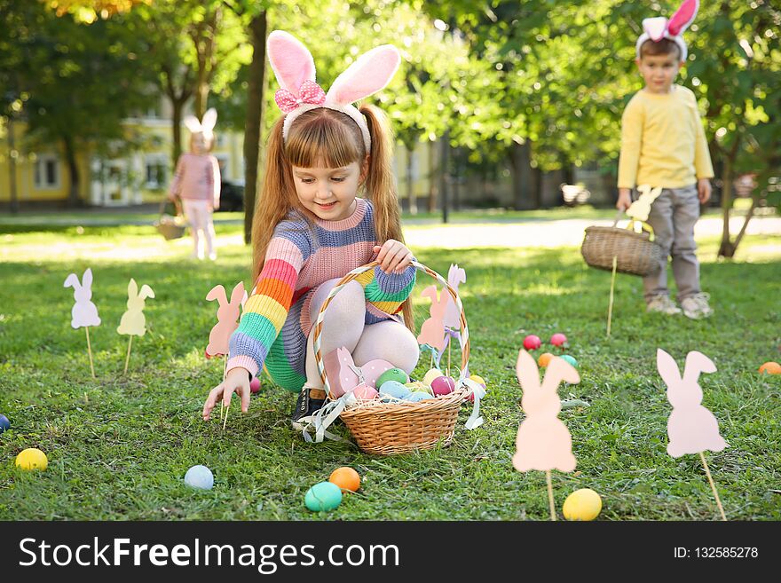 Cute little children hunting eggs in park. Easter tradition