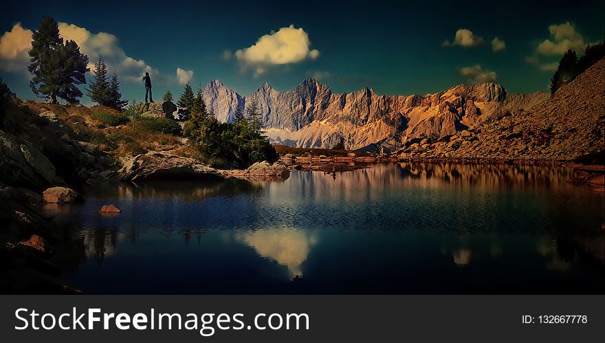 Traveller man with backpack enjoying beautiful view in mountain, blue sky, positive emotions,travelling lifestyle.Lake,stones,,trees,blue sky,peaks.Reflexion on water,panoramic composite photo.Alps .