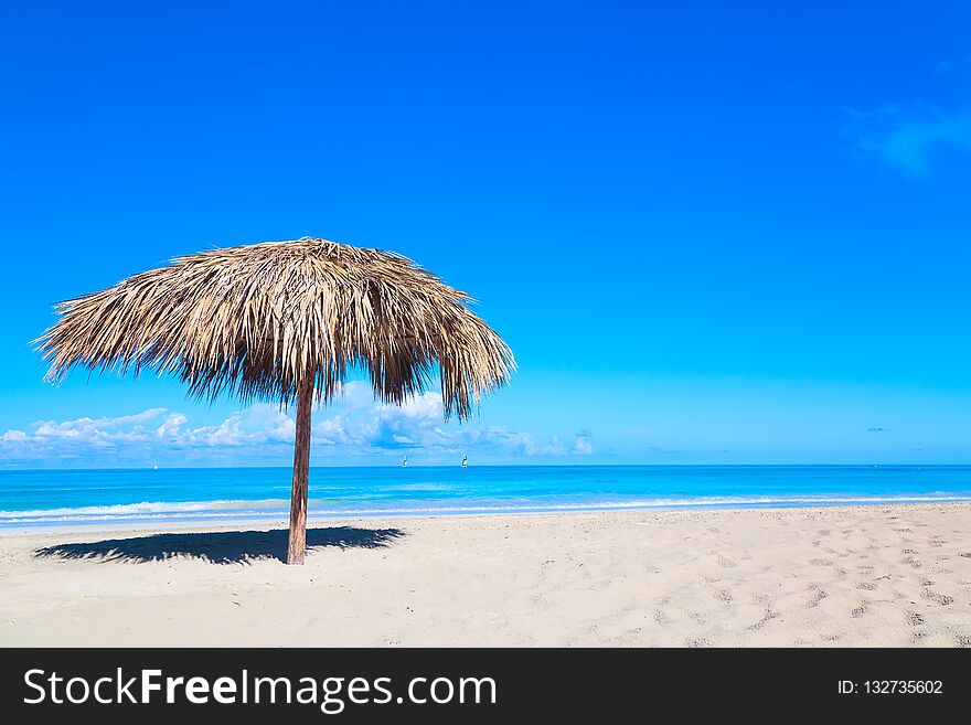 Straw umbrella on empty seaside beach in Varadero, Cuba. Relaxation, vacation idyllic background.