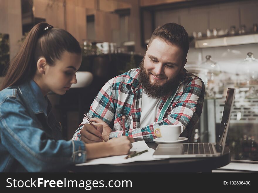 Young People Fill Out Documents While In A Cafe