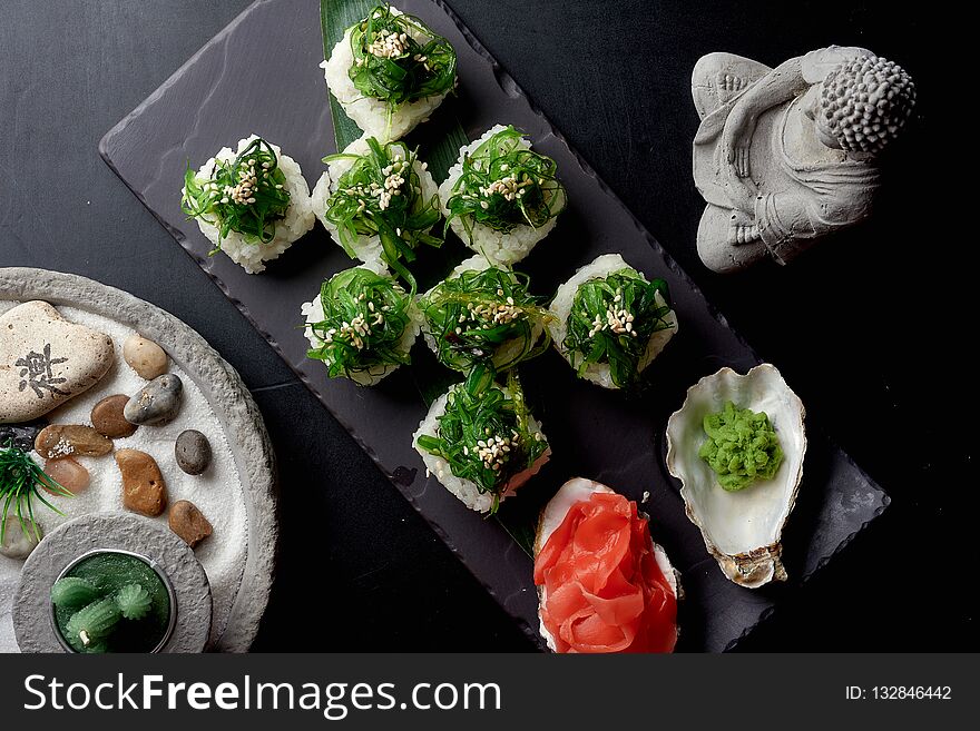 Top view of healthy green sushi rolls served with wasabi and pickled ginger. Near on the table two pots with succulents.