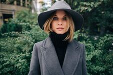 Photo Of Young Blonde In Gray Coat On Blurred Background Of City, Green Trees Royalty Free Stock Image