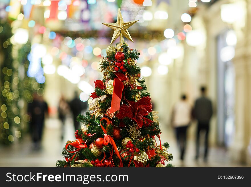 Photo of decorated Christmas tree with gold and red balls, star in store.