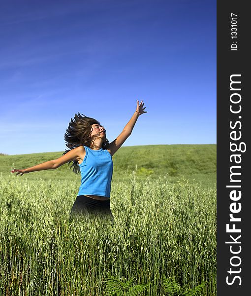 Young active woman jumping on a green field