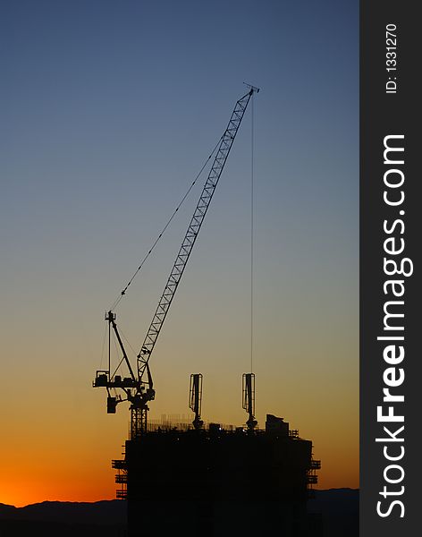 A construction site with the sun coming up behind it, silhouette. A construction site with the sun coming up behind it, silhouette