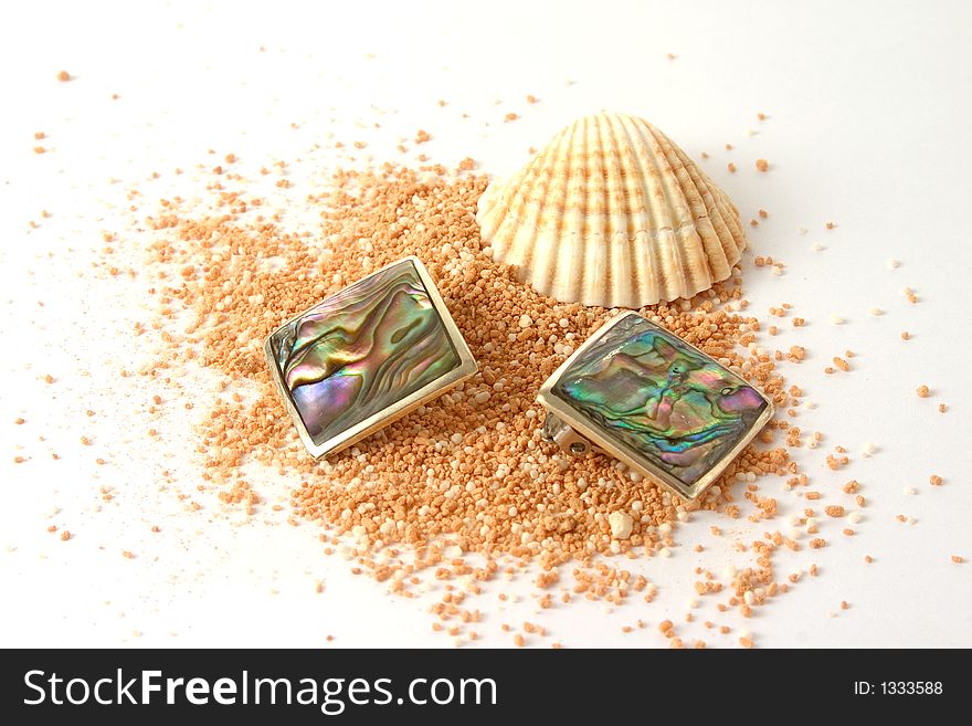 A shell and pearl earrings on beachsand. A shell and pearl earrings on beachsand