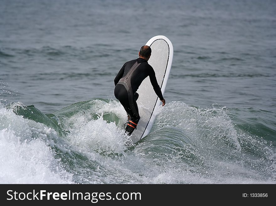 Surfer with a longboard on top of the wave