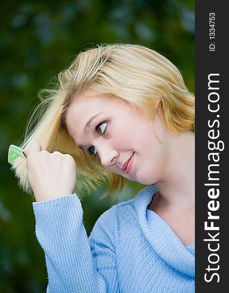 Beautiful Yong Blonde Girl With Blue Eyes Combing Her Hair