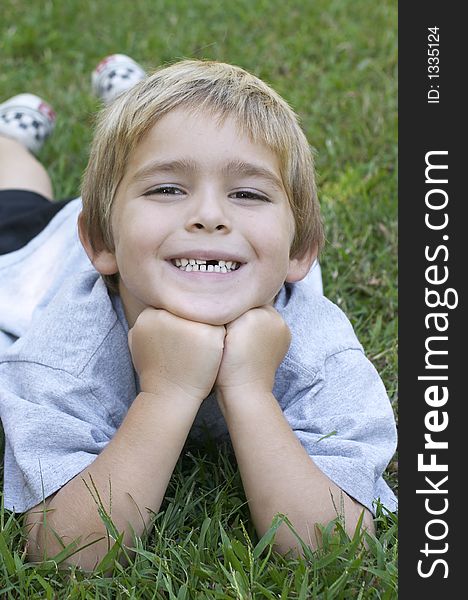 Young boy on grass smiling. Young boy on grass smiling