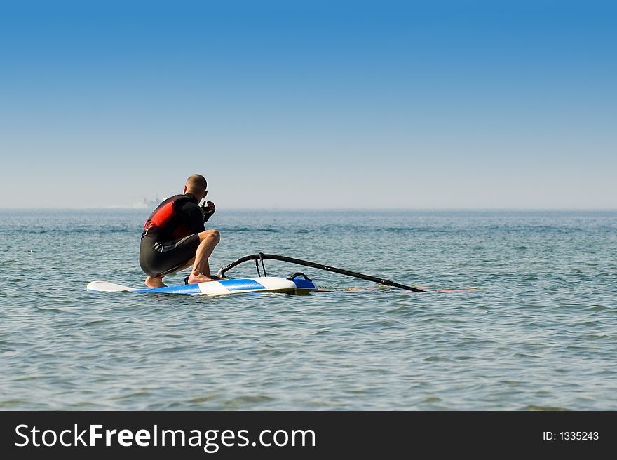 Windsurfer waiting for the wind at sea on a sunny day. Windsurfer waiting for the wind at sea on a sunny day.