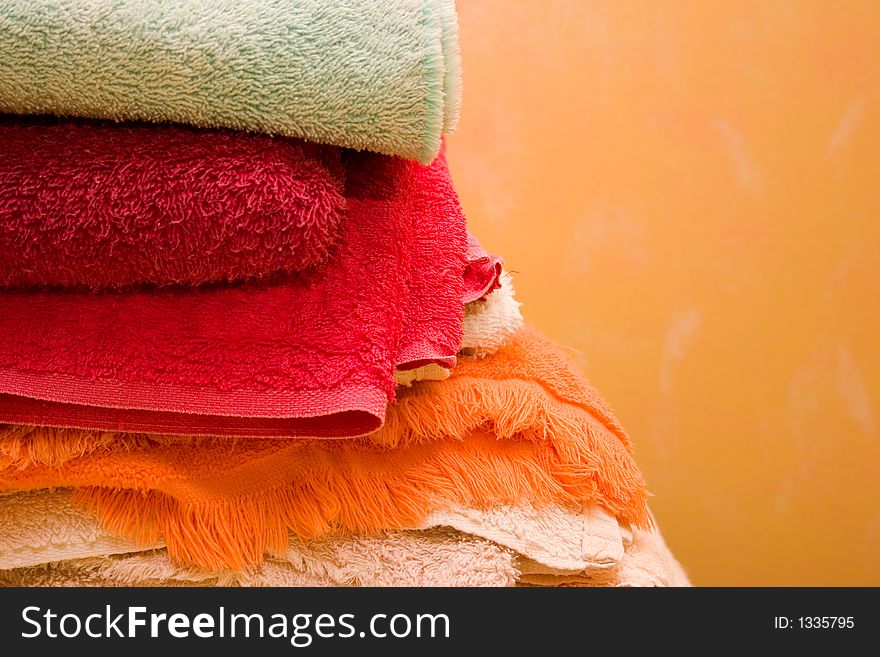 A Stack of colorful towels against a wall.
