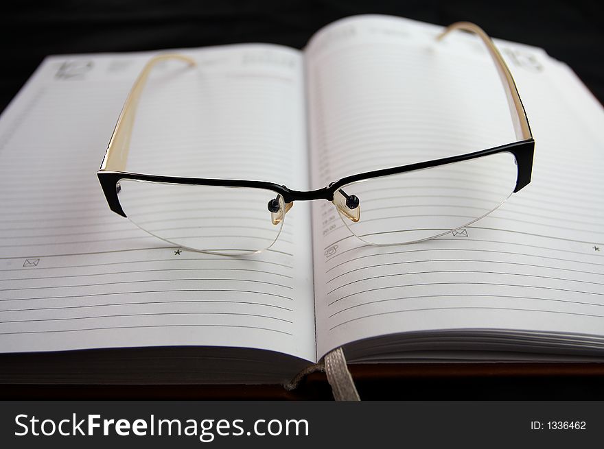 Eyeglasses on notebook on black