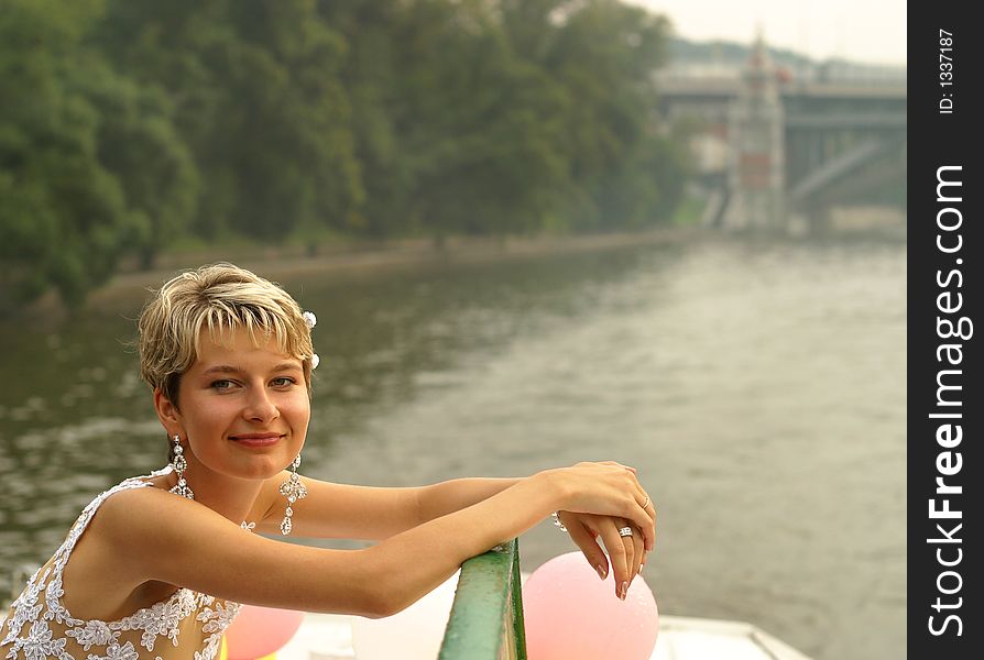 Smiling bride stands by the steam-ship