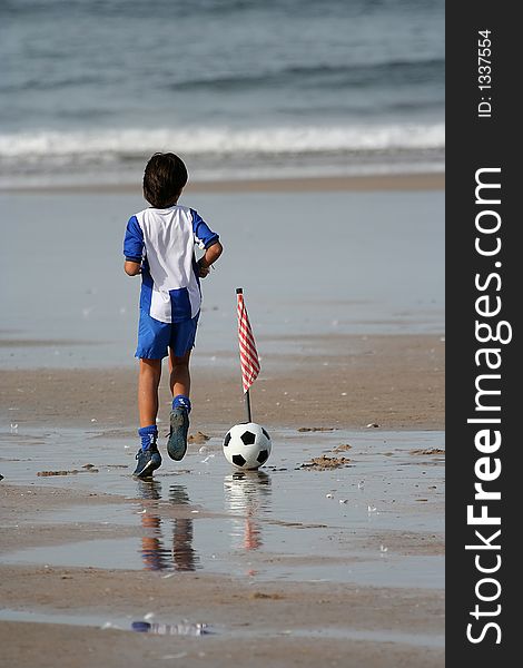 Boy playing soccer in the beach