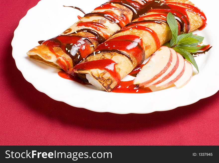 Pancake rolls stuffed with whipped cream and covered with strawberry jam coating pralin�e decorations. Pancake rolls stuffed with whipped cream and covered with strawberry jam coating pralin�e decorations