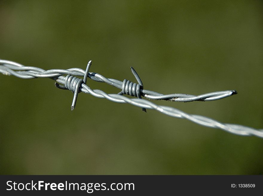 Close-up of barbwire in shallow DOF against green pasture field