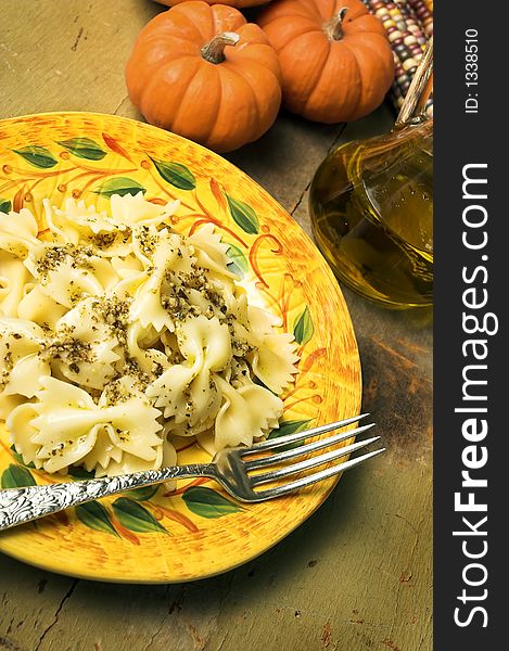 Farfalle pasta with italian pesto.Pumpkins and olive oil in background. Farfalle pasta with italian pesto.Pumpkins and olive oil in background