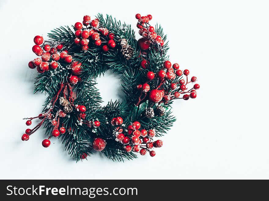 Christmas decorative wreath of holly, ivy, mistletoe, cedar and leyland leaf sprigs with red berries over white background.