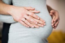 Close Up Of Male And Female Hands Resting On Pregnant Womans Stomach Stock Photos