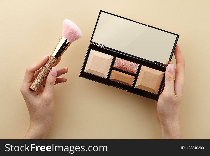 Make up artist holding sculptor palette and brush in hands on beige background, close up view. Make up artist holding sculptor palette and brush in hands on beige background, close up view