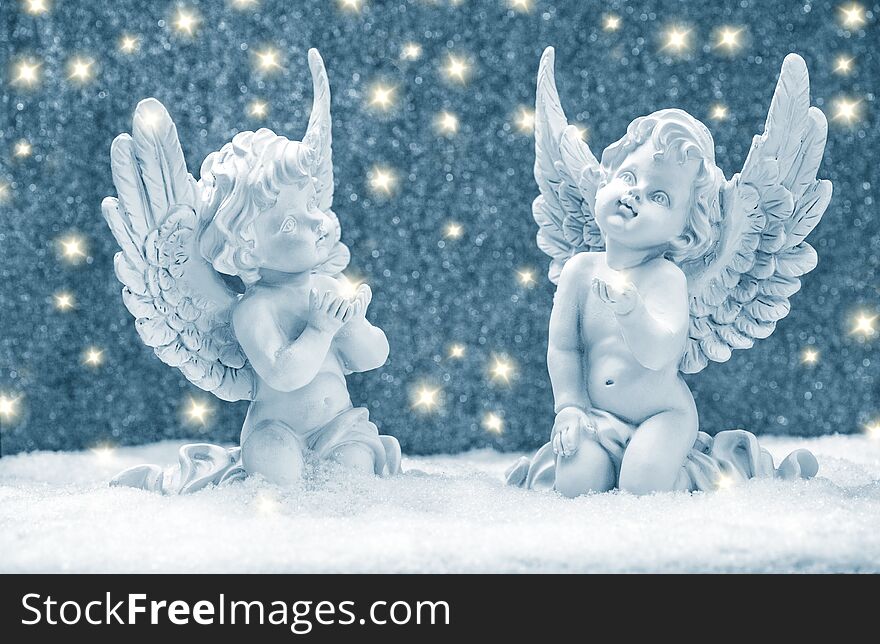Little guardian angels in snow with golden lights. Christmas decoration