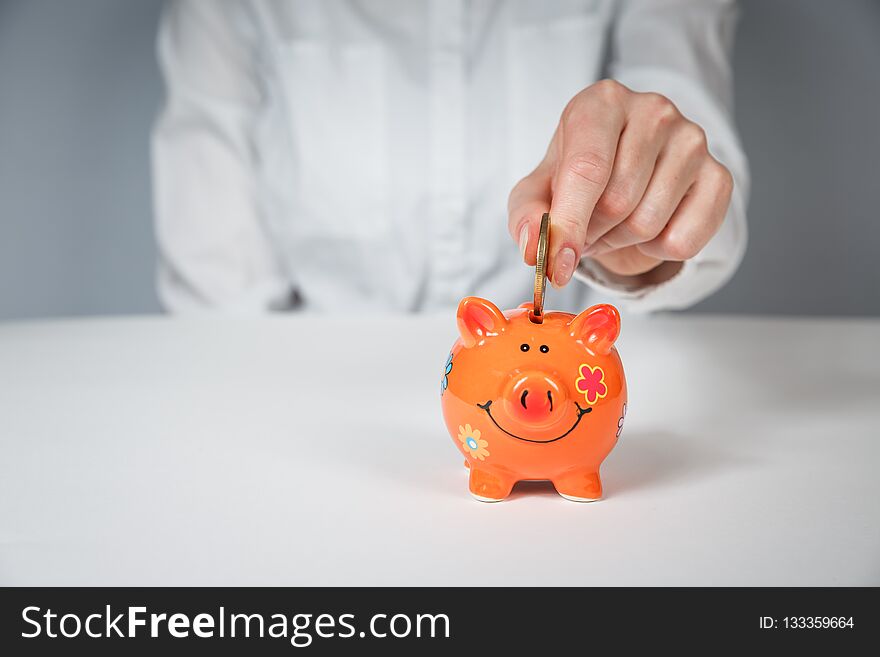 Savings, money, annuity insurance, retirement and people concept - close up of senior woman hand putting coin into piggy bank