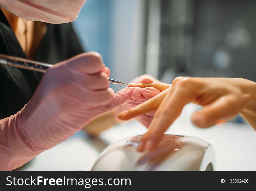 Beautician in pink gloves sticks the nails of female client, manicure in beauty salon. Manicurist doing hands care cosmetic procedure. Beautician in pink gloves sticks the nails of female client, manicure in beauty salon. Manicurist doing hands care cosmetic procedure