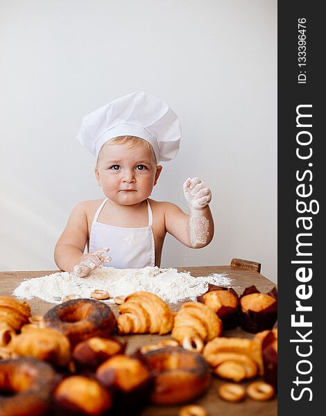 A little boy in a chef`s suit with flour and rolls. A little boy in a chef`s suit with flour and rolls.