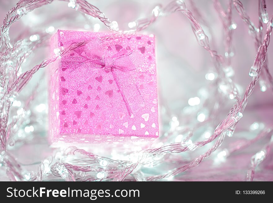 Pink gift box with a bow and small hearts on a silver blurred background. Beautiful sparkling gift for all holidays. Pink gift box with a bow and small hearts on a silver blurred background. Beautiful sparkling gift for all holidays