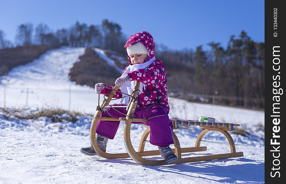 Little girl enjoying a sleigh ride. Child sledding. Children play outdoors in snow. Outdoor fun for family Christmas vacation
