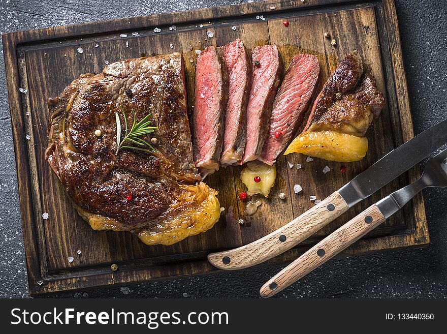 Grilled beef steak ribeye medium rare on wooden cutting board. Top view. Grilled beef steak ribeye medium rare on wooden cutting board. Top view.