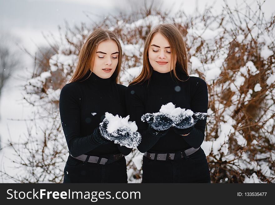 Cute girls walking in a winter park. Sisters have fun with snow. Cute girls walking in a winter park. Sisters have fun with snow