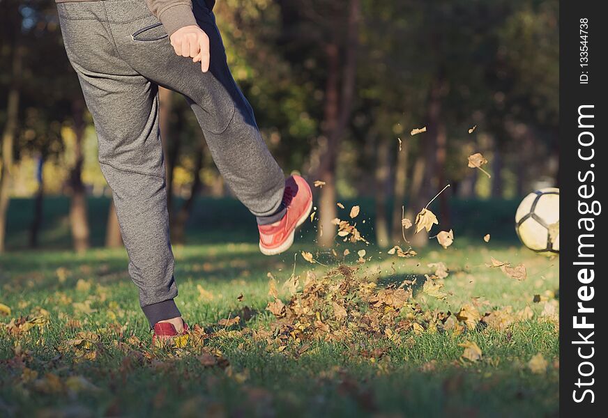 Soccer Player Kicking Football in the Park on a Sunny Autumn Day