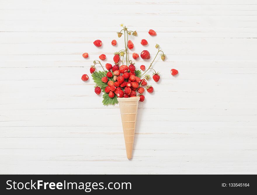 Waffle cone with strawberries on wooden background
